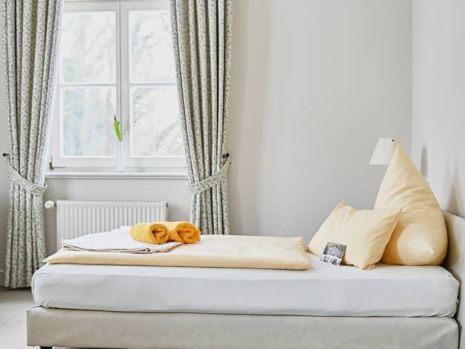 Ein gemütliches Bett in einem einladenden Raum, umgeben von warmen Farben und sanfter Beleuchtung.