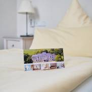 Ein gemütliches Schlafzimmer mit einem einladenden Bett und einem Infoheft, das auf der Bettdecke liegt.