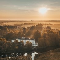 Luftaufnahme der Psychosomatischen Klinik am Fluss bei Sonnenuntergang, die Ruhe und Harmonie ausstrahlt.