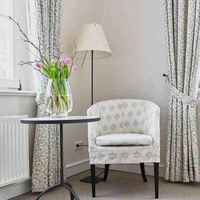 Ruhiges Zimmer in der psychosomatischen Klinik, mit einem Stuhl und einer Vase, die auf dem Tisch steht.